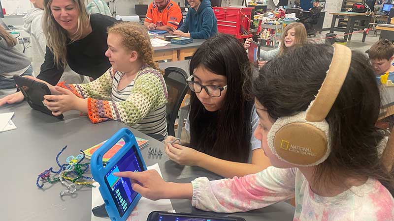 3 students coding on computers in fablab