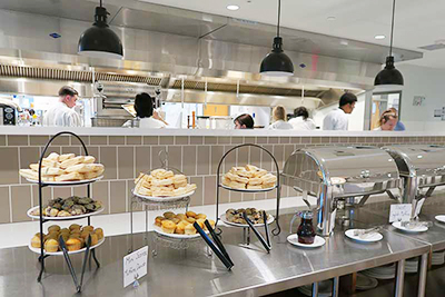 Photo of culinary arts students cooking in background with delicious pastries in foreground