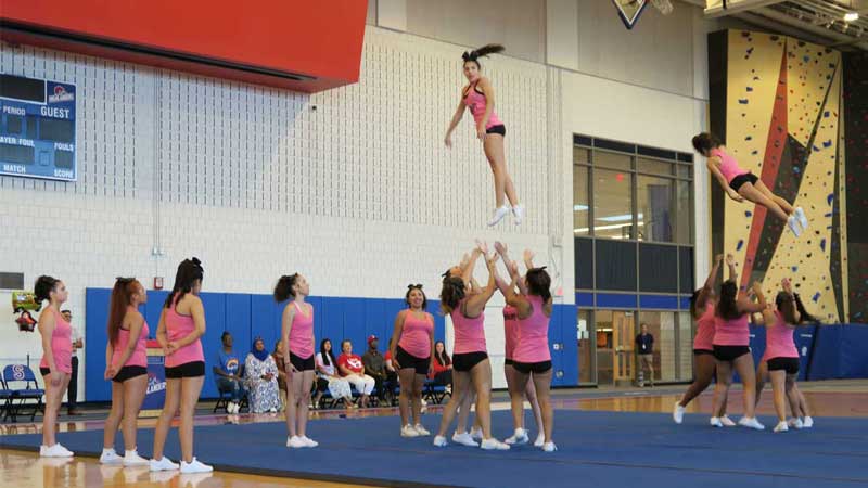 Cheerleading squad throws two team members in the air in SHS field house