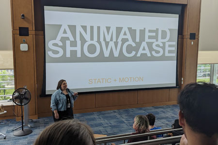 Students and friends watch art teacher being an end-of-year presentation of student animation in the Highlander Forum lecture hall