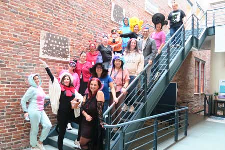 Photo of central administrative staff standing on a tall staircase and wearing Halloween costumes.