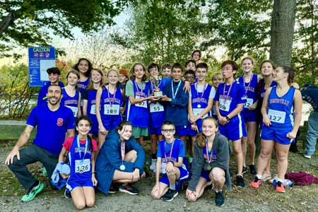 Middle Grades Cross Country team poses in front of body of water and trees with the boy's team GBL trophy
