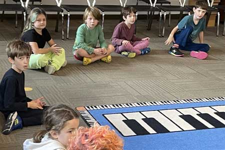 Second grades students at Kennedy sitting on the floor in music classroom