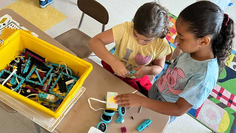 Two elementary students in the Summer Program for English Language Learners work together to build a robot out of Legos [TM]