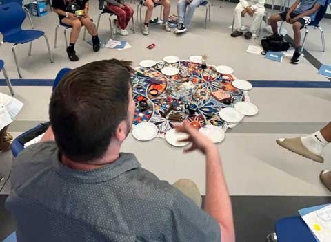 Students and staff member sit in a restorative justice circle in a classroom